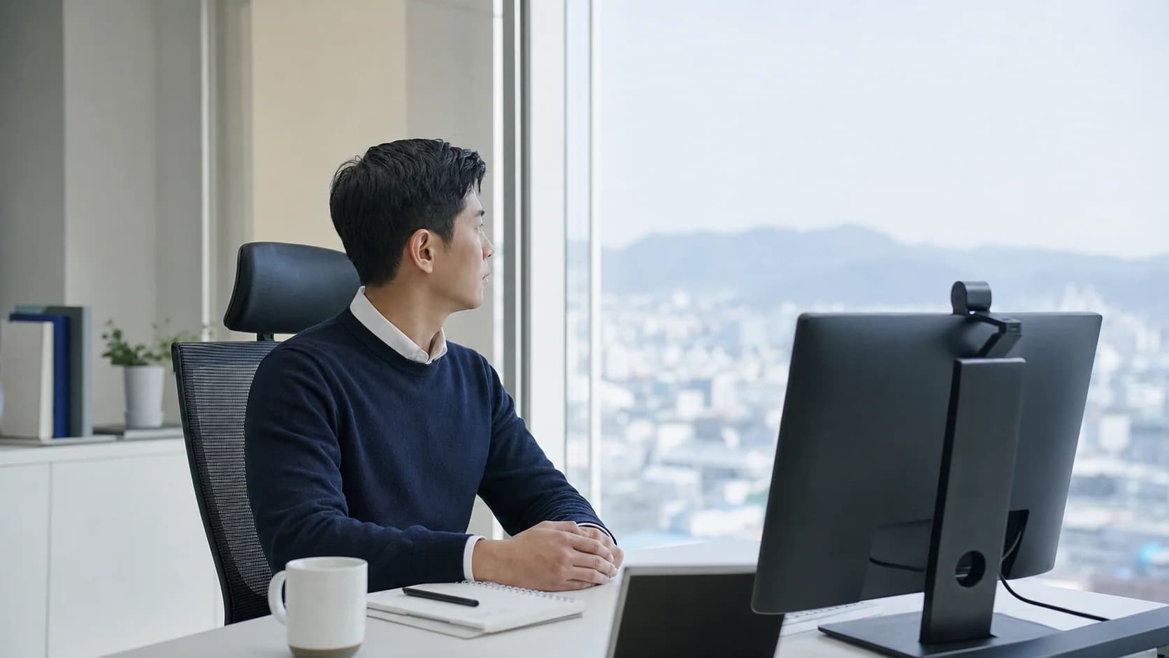 화상회의를 듣는 중 모니터에서 시선을 돌려 먼 창밖을 보는 참가자