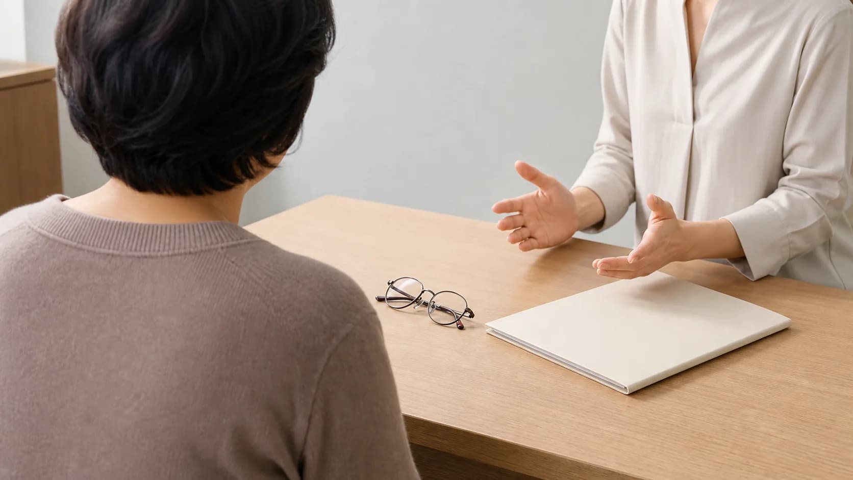 안경과 빈 자료철을 두고 생활 불편과 검사 판단을 상담하는 한국인 성인