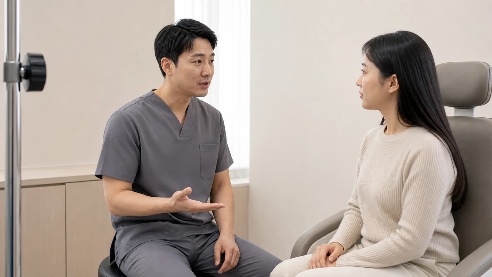 검사실에서 장비 옆에 서서 화면이 아니라 수검자 쪽을 보며 설명하는 검사자