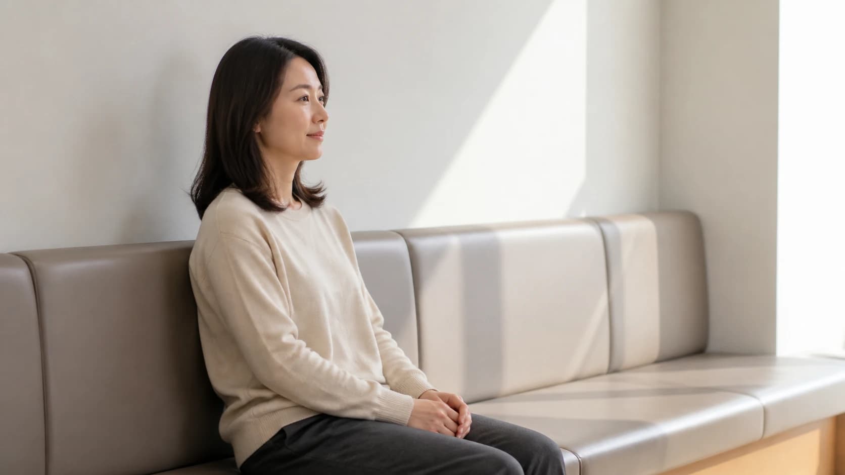 낮 빛이 드는 검사 대기 공간에 앉아 있는 인물의 측면
