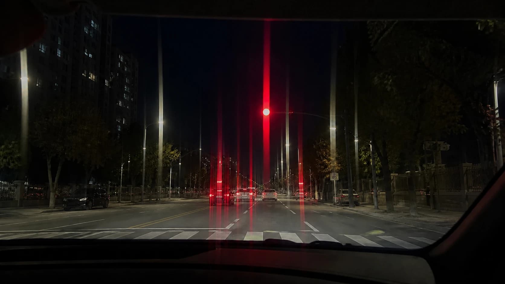 차 안에서 본 야간 도로에서 신호등과 건너편 불빛이 한 방향으로 길게 늘어져 보이는 장면