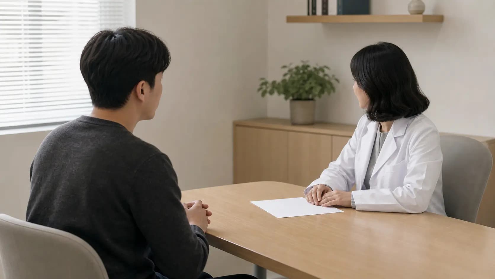 상담 테이블에 놓인 빈 종이를 사이에 두고 검사 결과 설명을 듣는 모습